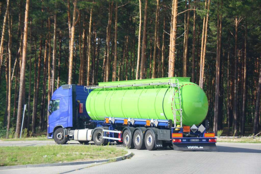 a large green tanker truck driving down a road